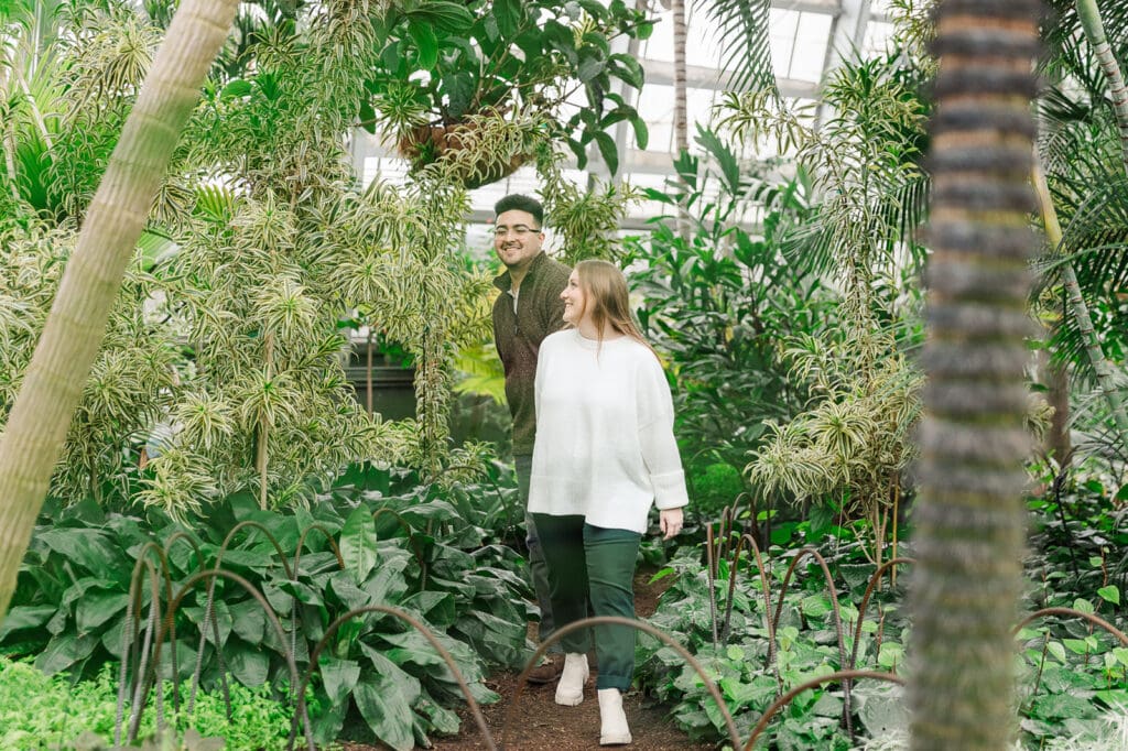 Couple walking through a tree-themed room at Garfield Park Conservatory during their engagement session.