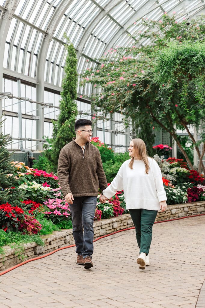 Couple walking together holding hands while looking at one another during their engagement session in Chicago