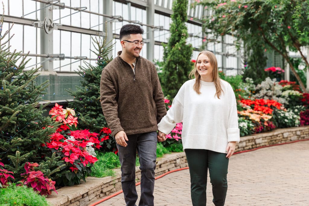 Couple walking hand in hand laughing with one another during their engagement session at Garfield Park Conservatory.