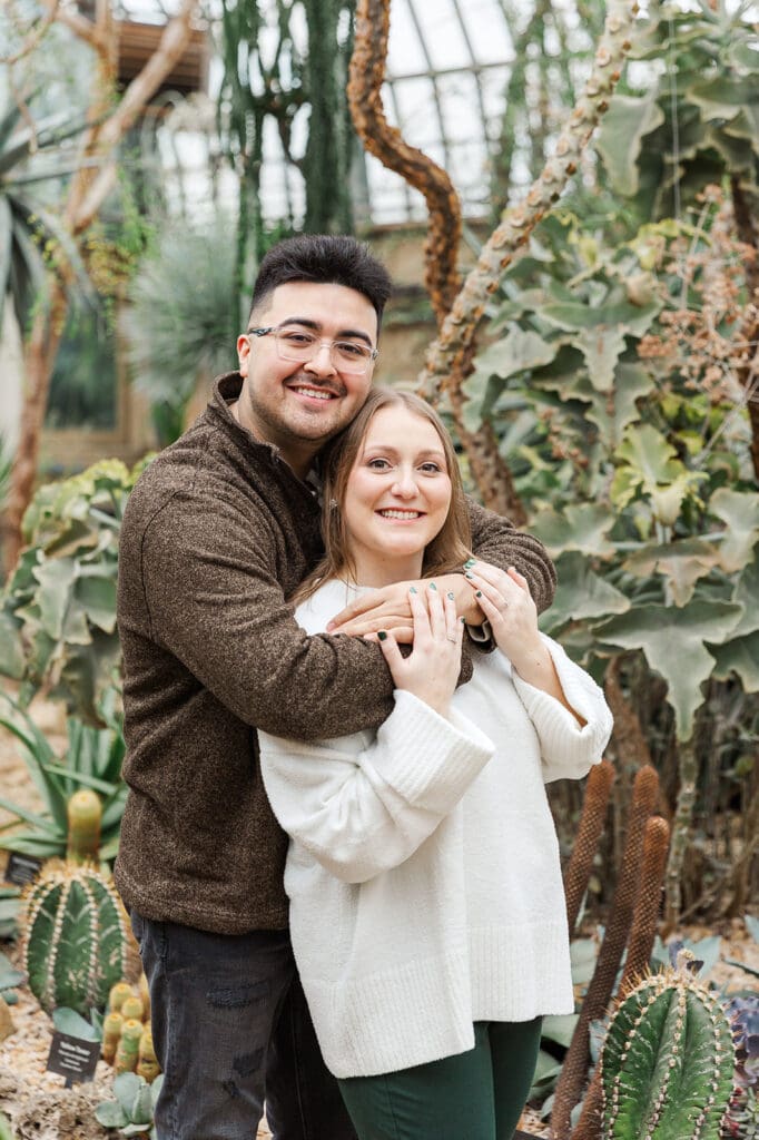 Couple standing and smiling together with their arms wrapped around one another for their engagement session in Chicago