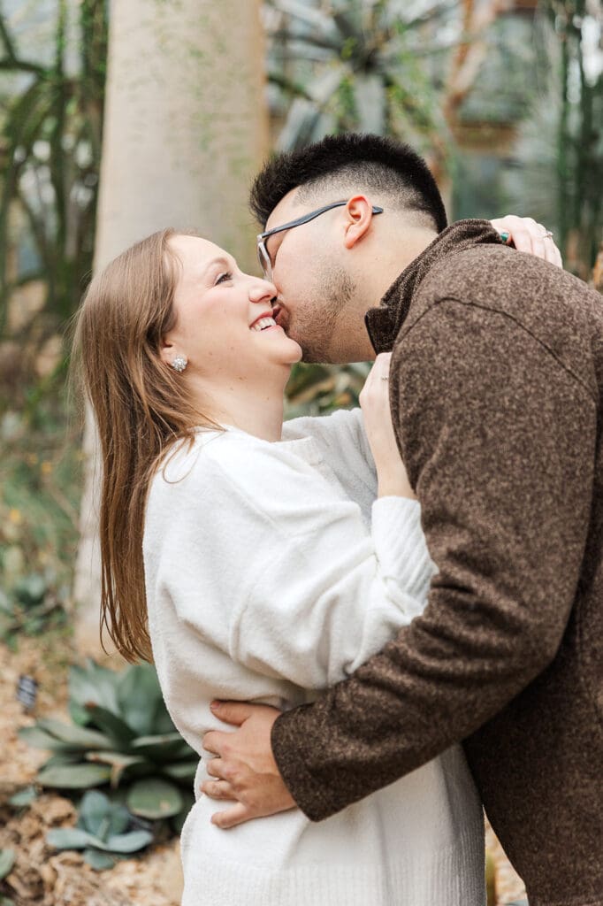 A couple sharing laughs and kisses during their engagement session at Garfield Park Conservatory