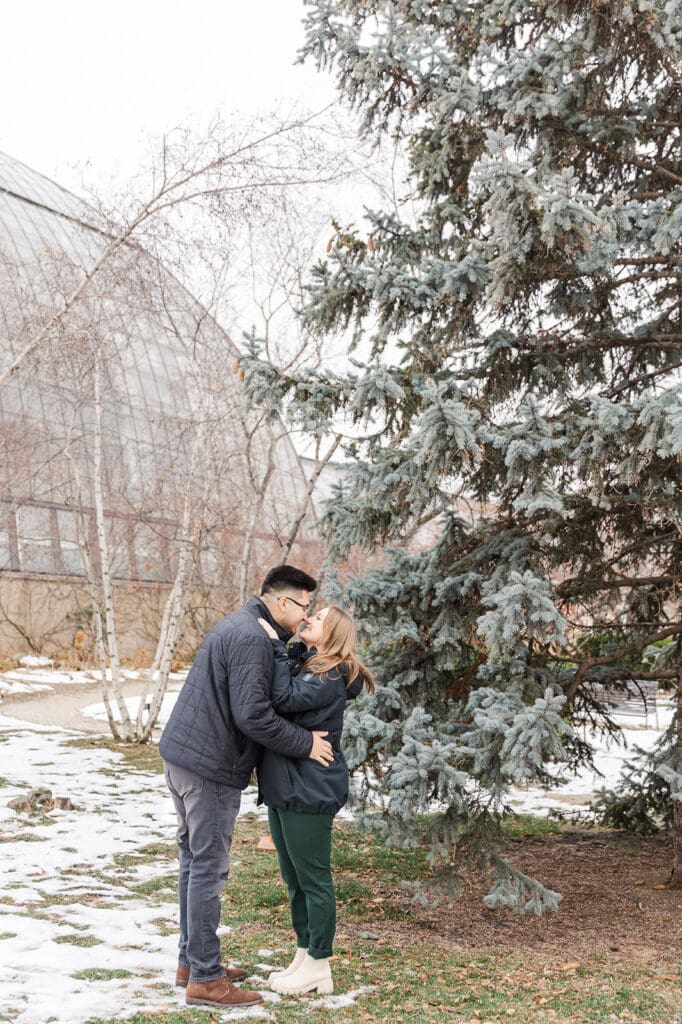 A couple kissing during their winter engagement session in Chicago outside of the Garfield Park Conservatory